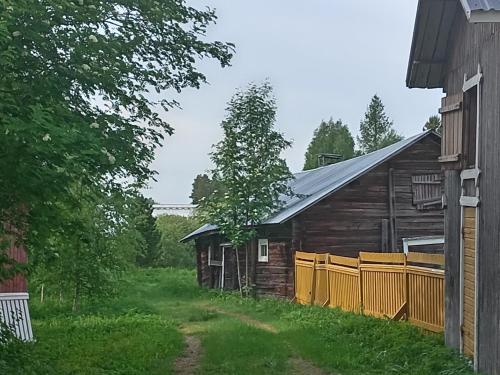 an old barn with a fence next to a house at Huoneita Pyrrön pirtissä in Oulainen
