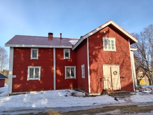 a red house with a door in the snow at Huoneita Pyrrön pirtissä in Oulainen