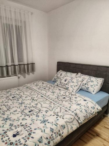 1 dormitorio con 1 cama con manta y almohadas en Apartman Panić, en Bosanska Gradiška