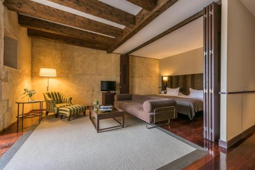 ein Schlafzimmer mit einem Bett, einem Sofa und einem Stuhl in der Unterkunft Hospes Palacio de San Esteban in Salamanca