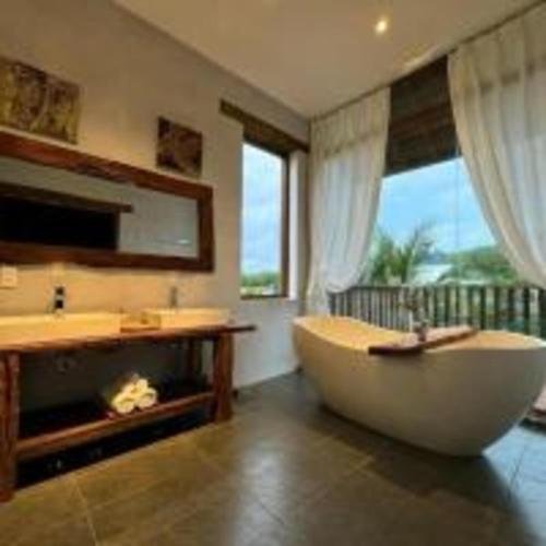 ein großes Badezimmer mit Badewanne und Waschbecken in der Unterkunft The Cottage Hồ Tràm - Venuestay in Thuận Biên