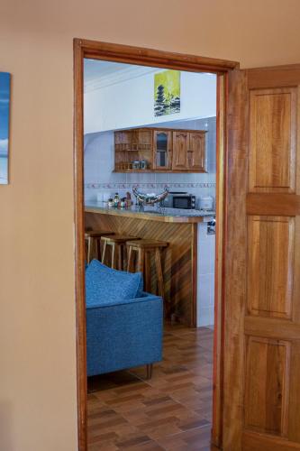 a door leading into a kitchen with a blue couch at Casa De Leela Self Catering Guest House in La Digue