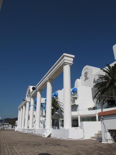 a large white building with columns and palm trees at Hotel Limani in Setouchi