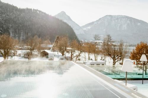 a hot tub with snow covered mountains in the background at Seehotel Berau in St. Wolfgang