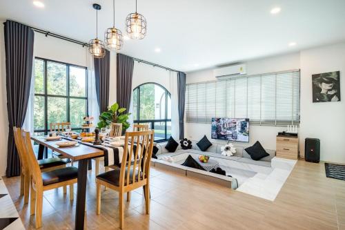 un soggiorno con un divano, un tavolo e delle sedie di Gift Pool Villa Khaoyai เขาใหญ่ บ้านพักเขาใหญ่ พูลวิลล่าเขาใหญ่ a Ban Nong Ka Cha