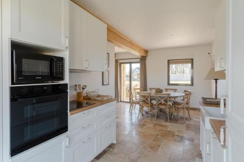 eine Küche mit weißen Schränken und einem Tisch mit Stühlen in der Unterkunft Maison Morny Your Exquisite Retreat near Deauville in Cricquebœuf