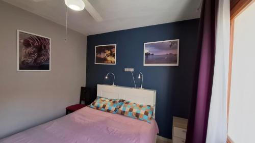 a bedroom with a purple bed and pictures on the wall at CASA DE LIVIA Vera Playa-bajo in Playas de Vera