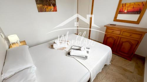 a bedroom with a white bed with a mirror and a dresser at SeS ORENETES in Cala en Blanes