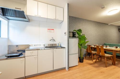 Una cocina con gabinetes blancos y una mesa de madera. en BP house 森ノ宮, en Osaka