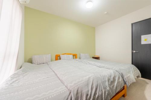 Un dormitorio con una cama grande con sábanas blancas. en BP house 森ノ宮, en Osaka