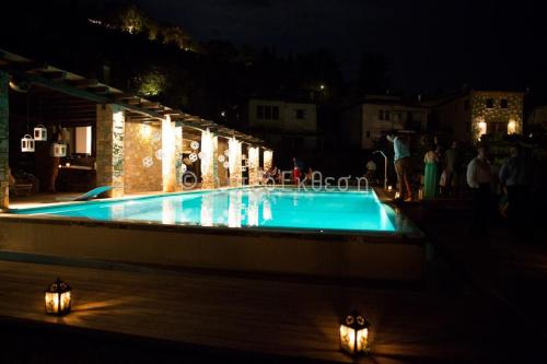 a swimming pool at night with people standing around it at Valeni Boutique Hotel & Spa in Portariá