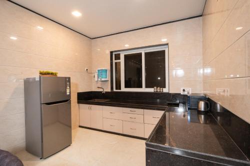 a kitchen with a black counter and a refrigerator at Seven Sands I Forest Pool Villa One I 6 BHK in Lonavala