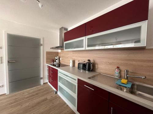 a kitchen with red cabinets and a sink at Ferienwohnung Haus Brenner in Seeg