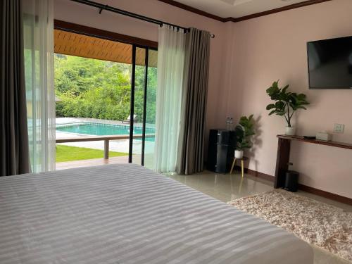 a bedroom with a bed and a view of a pool at Jindarin Villas จินดาริน คาเฟ่ in Ban Nong Sarai (1)