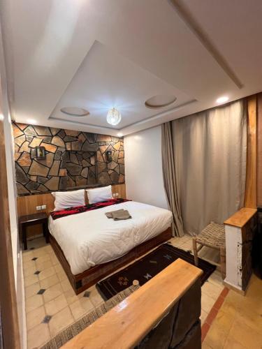 a bedroom with a bed and a stone wall at Canyon Dades Guest House in Akedim Msemrir