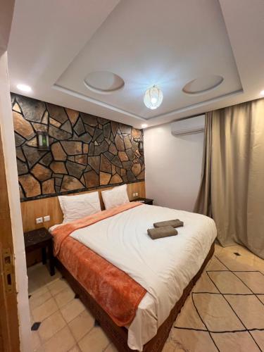 a bedroom with a bed with a stone wall at Canyon Dades Guest House in Akedim Msemrir