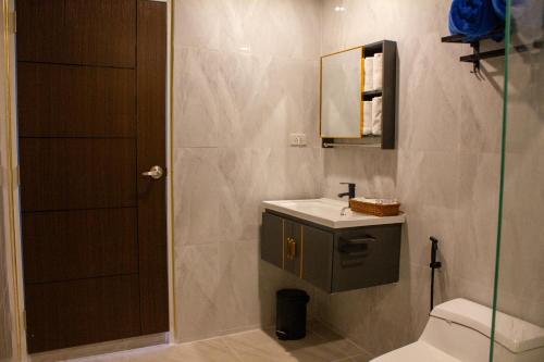 a bathroom with a toilet and a sink and a mirror at Jindarin Villas จินดาริน คาเฟ่ in Ban Nong Sarai (1)