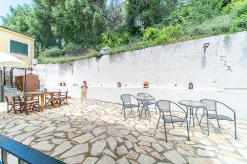 a patio with tables and chairs next to a wall at Spyridoula Studio 1 in Paleokastritsa