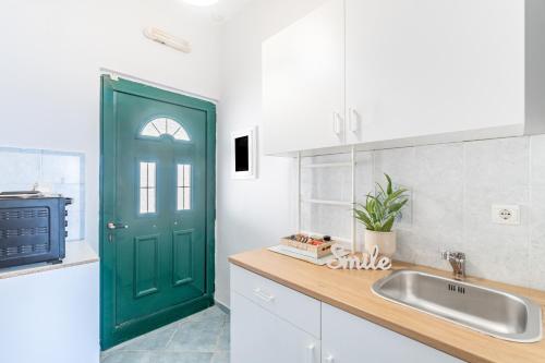 a green door in a white kitchen with a sink at Spyridoula Studio 1 in Paleokastritsa