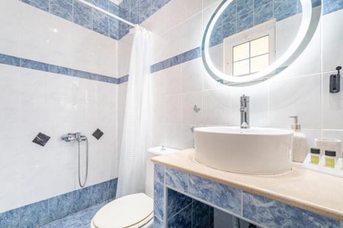a bathroom with a sink and a toilet and a mirror at Spyridoula Studio 4 in Paleokastritsa