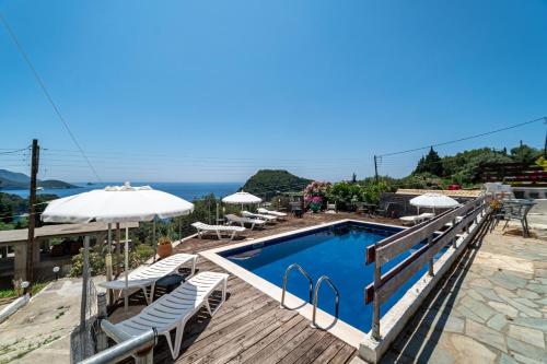 a pool with chairs and umbrellas on a deck at Spyridoula Studio 4 in Paleokastritsa