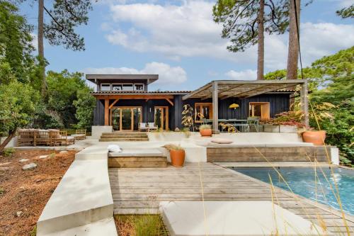 une maison avec une piscine et une maison dans l'établissement Villa Cap-Ferret, vue bassin-pinède, à Lège-Cap-Ferret