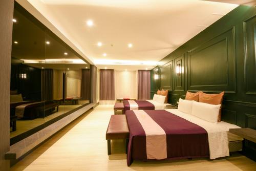 two beds in a room with green walls at Belle Song Motel in Shulin