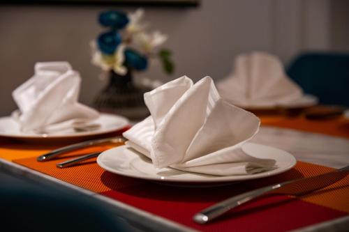 two white plates with napkins and utensils on a table at Hanoi Fiesta Central Hotel and Spa in Hanoi
