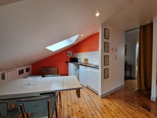 una cucina con pareti arancioni e tavolo e sedie di Garage de l'Hôtel a Clermont-Ferrand