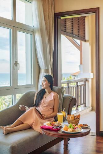 岘港Danang Marriott Resort & Spa的一位女士坐在沙发上，桌子上摆着食物