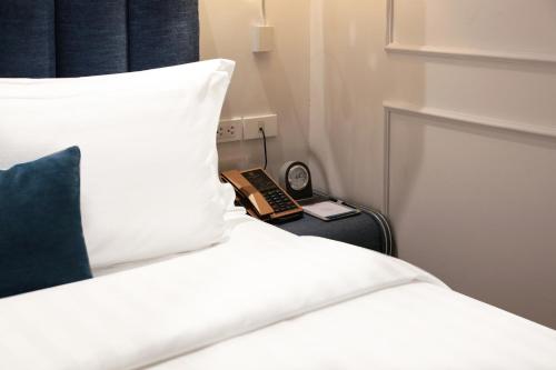 a bed with a pillow and a clock on a table at Hanoi Fiesta Central Hotel and Spa in Hanoi