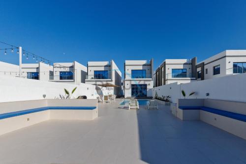 a large white building with blue windows and chairs at Serene 3BR Villa with Private Pool in Al Dana Island, Fujairah by Deluxe Holiday Homes in Fujairah