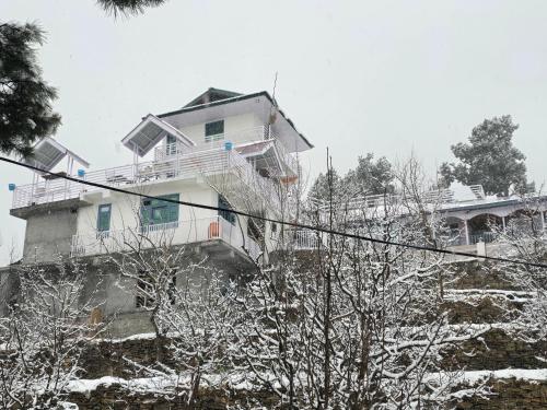 a house on a hill with snow on it at Kin Vatika Homestay in Kalpa
