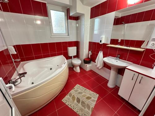 a red and white bathroom with a tub and a sink at Pensiunea La Vasile in Zalău