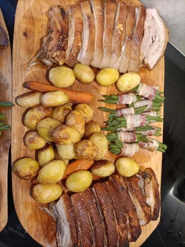 a wooden cutting board with meat and vegetables on it at GLASHÜTTE Kisújbánya Vadászház in Hosszúhétény