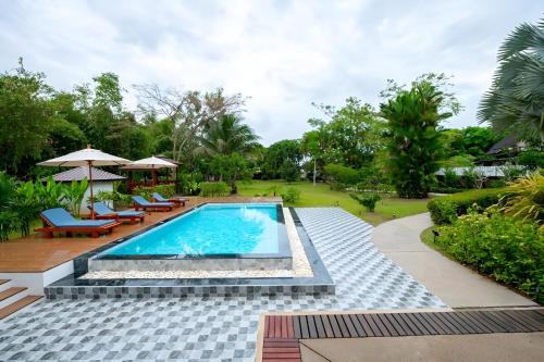a pool with chairs and umbrellas in a yard at Sriwaree Pool Villa Khao Lak - 8 meters pool - 3 bedroom - 2 bath in Khao Lak