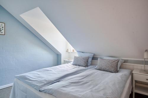 a bedroom with a white bed with two pillows at Hjorths Badehotel in Kandestederne