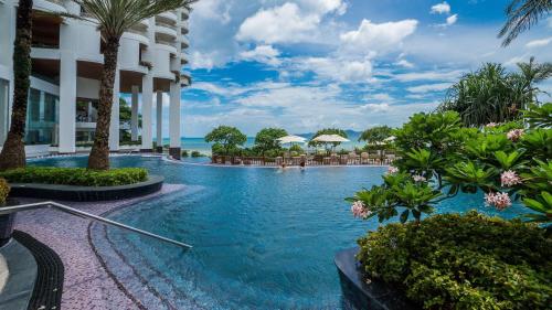 a pool at a resort with palm trees and chairs at Royal Cliff Grand Hotel Pattaya in Pattaya South