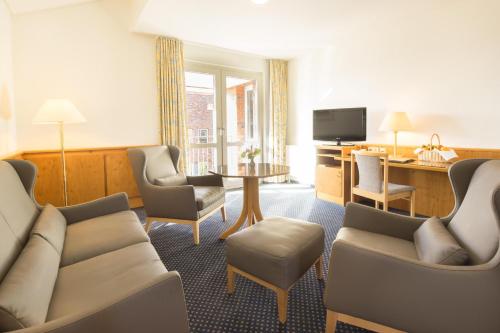 a hotel room with a couch and chairs and a table at Hotel Heidehof garni in Büdelsdorf