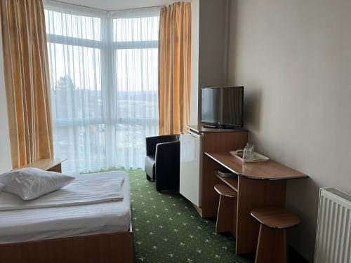 a hotel room with a bed and a desk and a television at Vila Crinul in Baile Felix