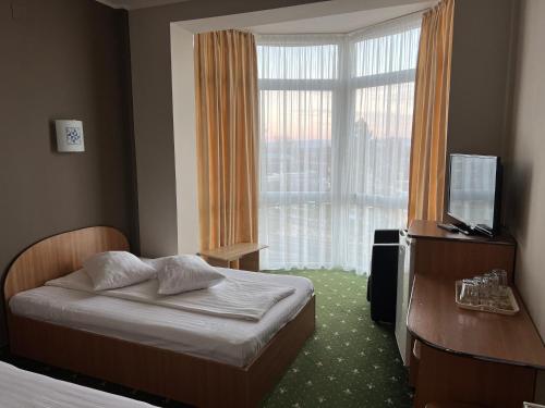 a bedroom with a bed and a television and a window at Vila Crinul in Baile Felix