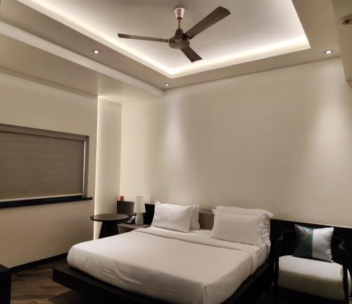 a bedroom with a bed and a ceiling fan at The Long D Hotel and Banquet Surat Airport Rd in Surat