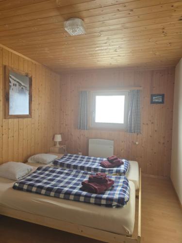 a bedroom with a bed with a blue and white checked blanket at Gotschnagrat Bergrestaurant- Best Panoramic View in Klosters