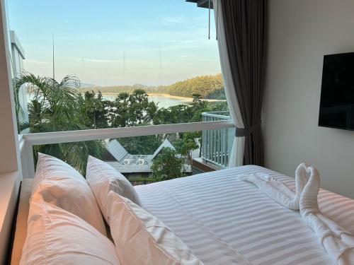 a bed in a room with a view of a balcony at Beachfront Bliss at Naiyang Phuket by ALPHATEL in Phuket