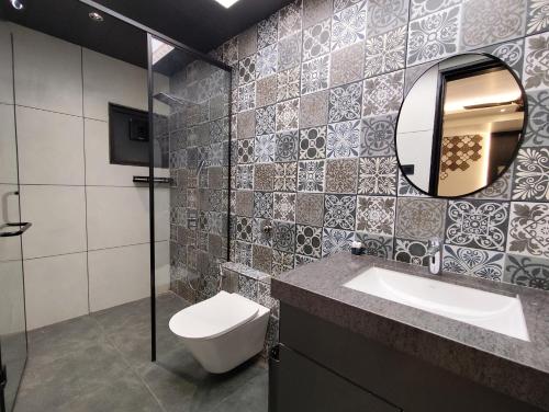 a bathroom with a toilet and a sink and a mirror at The Long D Hotel and Banquet Surat Airport Rd in Surat