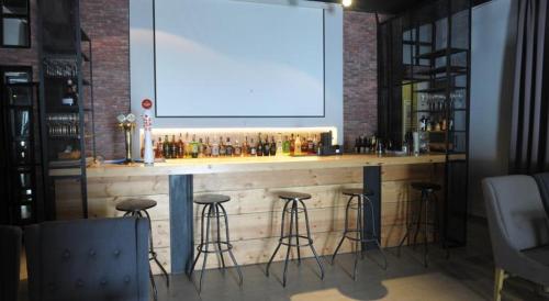 un bar con sgabelli e un grande schermo di Gudauri Lounge Apartment a Gudauri