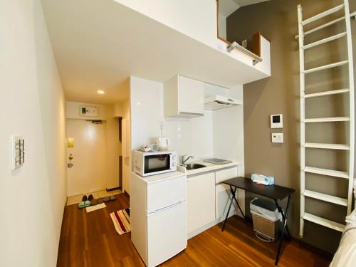 a small white kitchen with a microwave and a small table at Okubo House 3F SJ0277 in Tokyo