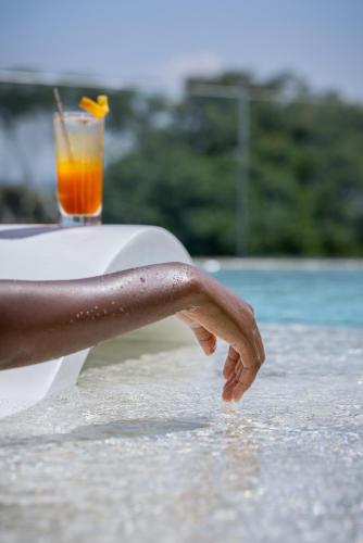 a person is sitting on the beach with a drink at Gem Forest Hotel Nairobi - MGallery Collection in Nairobi