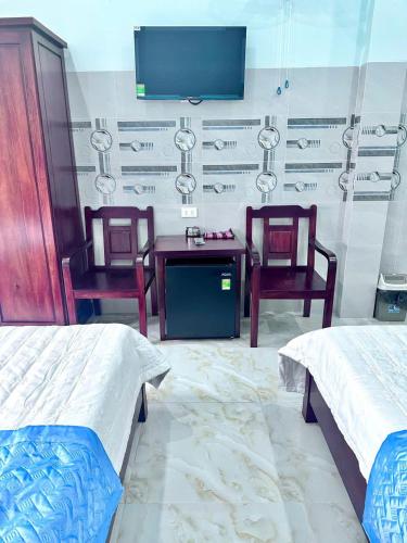 a bedroom with two beds and a tv and two chairs at Hotel PHƯƠNG HOA in Quy Nhon
