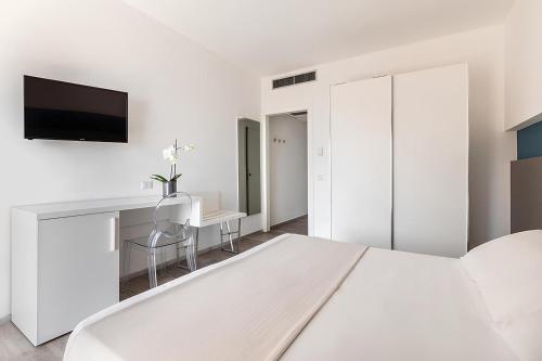a white bedroom with a bed and a desk at Hotel Serapo in Gaeta